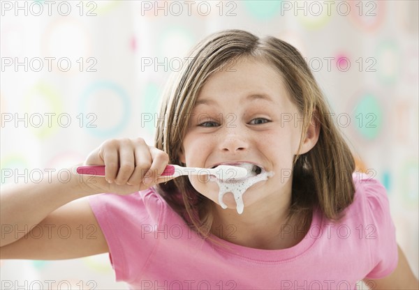 Girl (10-11) brushing teeth in messy way. Photo : Mike Kemp