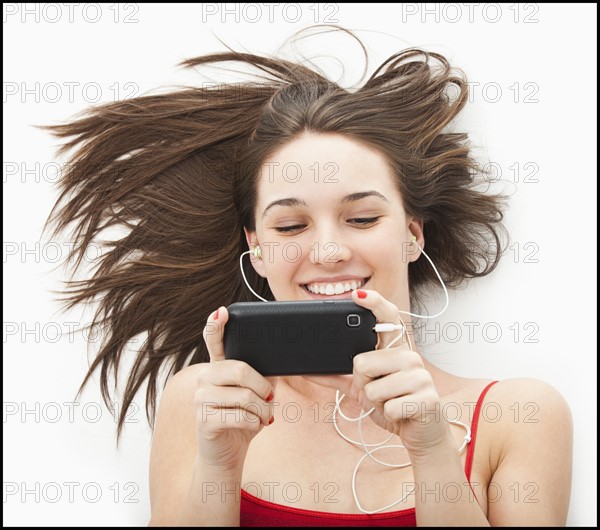 Young woman listening to mp3 player. Photo : Mike Kemp