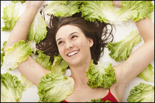 Young woman lying in lettuce leaves. Photo : Mike Kemp