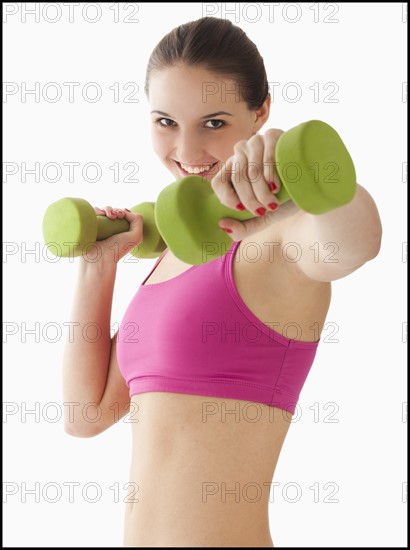 Studio portrait of young woman exercising with hand weights. Photo : Mike Kemp