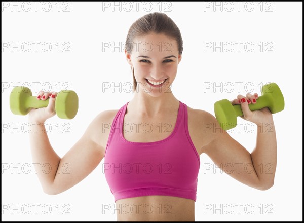 Studio portrait of young woman exercising with hand weights. Photo: Mike Kemp