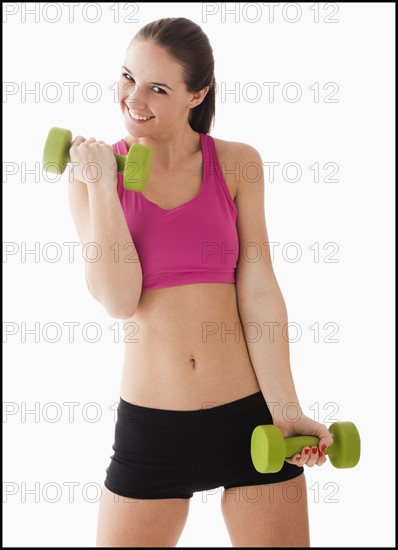 Studio portrait of young woman exercising with hand weights. Photo: Mike Kemp