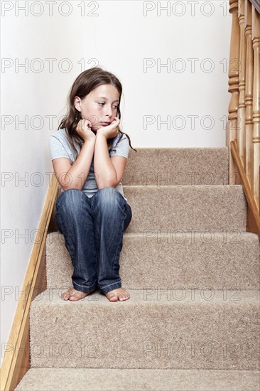 Girl (8-9) sitting on stairs. Photo : Justin Paget