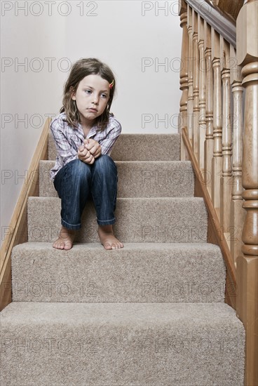 Girl (8-9) sitting on stairs. Photo : Justin Paget