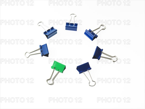 Blue and green bulldog clips on white background. Photo: David Arky