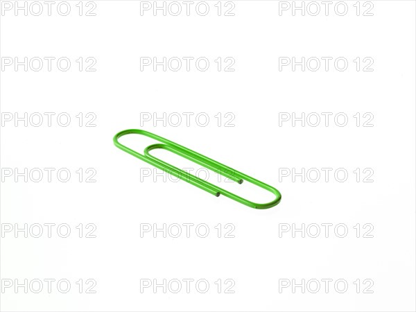 Green paper clip on white background. Photo : David Arky