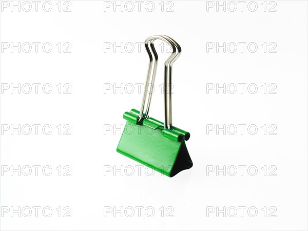 Green bulldog clip on white background. Photo: David Arky