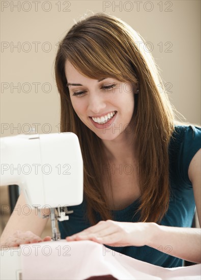 Smiling young woman using sewing machine. Photo: Mike Kemp