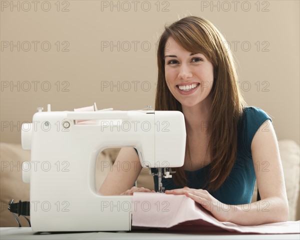 Portrait of smiling young woman using sewing machine. Photo : Mike Kemp