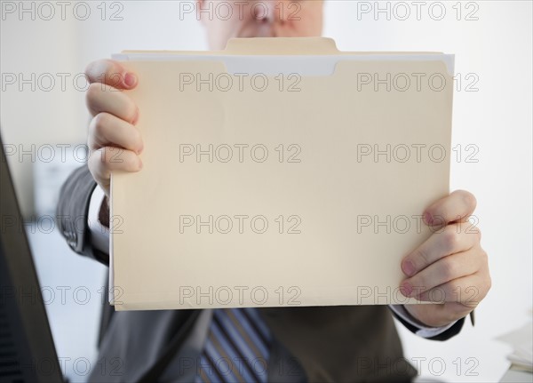 Businessman holding folder. Photo : Jamie Grill Photography