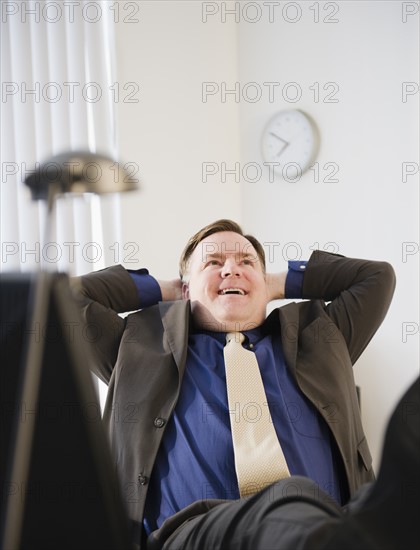 Businessman relaxing in office. Photo : Jamie Grill Photography