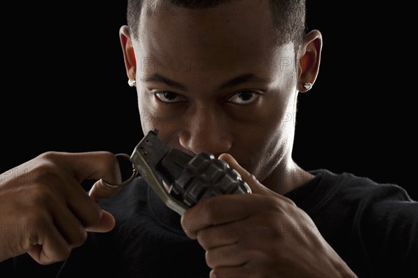 Studio portrait of young man holding grenade. Photo: Mike Kemp