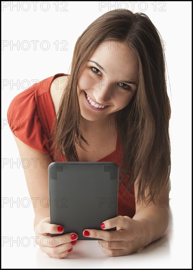 Studio portrait of young woman using electronic organizer. Photo: Mike Kemp