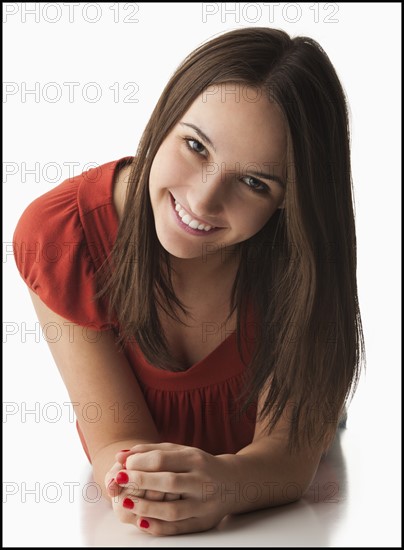 Studio portrait of young woman lying down, smiling. Photo : Mike Kemp