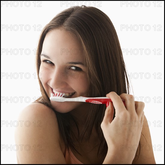 Studio portrait of young woman brushing teeth. Photo: Mike Kemp