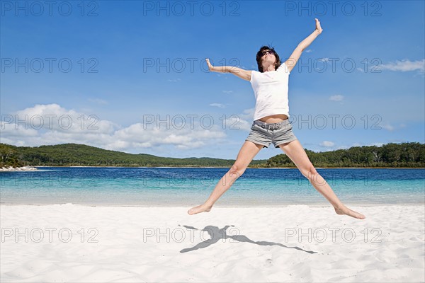 Fraser Island, Australia, Woman cheering on beach. Photo : Justin Paget