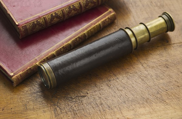 Close up of antique telescope and books.