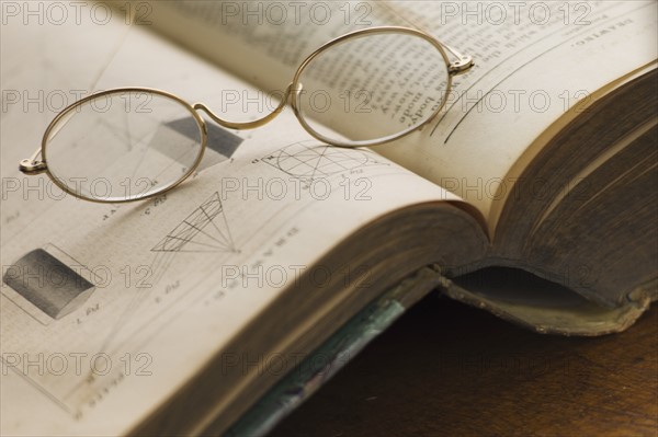 Close up of antique glasses lying on open book.