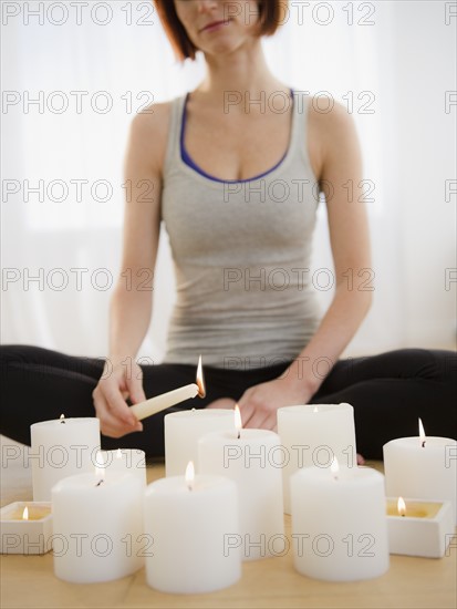 Woman preparing for meditation and igniting candles. Photo: Jamie Grill Photography