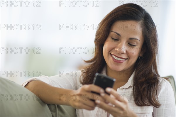 Smiling woman sitting texting on mobile phone.