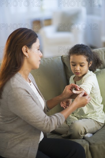 Mother applying bandaid on daughter's (6-7) arm.