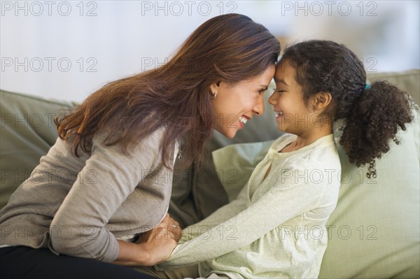 Mother playing with daughter ( 6-7) on sofa.