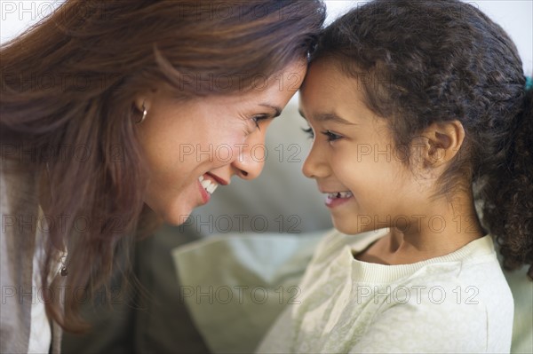 Mother laughing with daughter (6-7) face to face.