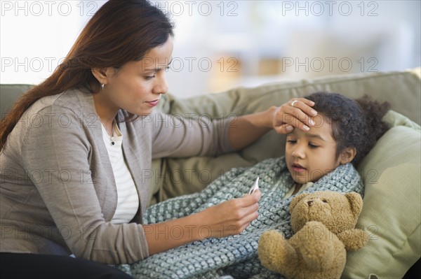 Mother taking daughter's (6-7) temperature.