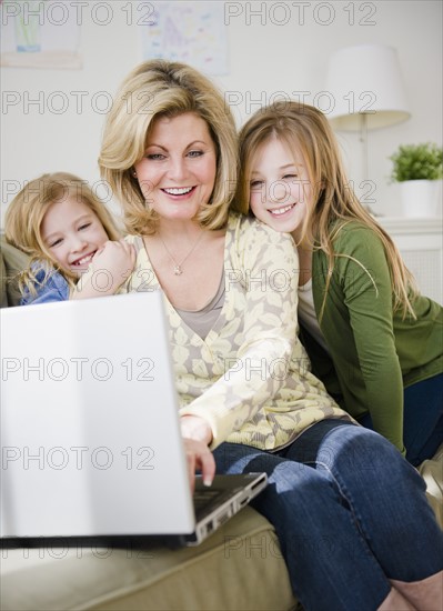 Mother and daughters (8-11) using laptop. Photo: Jamie Grill Photography