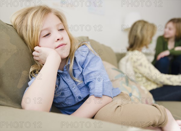 Girl (8-9) sitting on sofa. Photo : Jamie Grill Photography