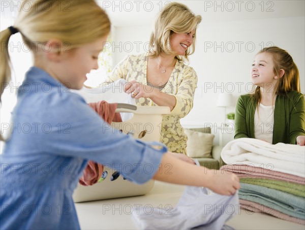 Mother and daughters (8-11) doing laundry. Photo: Jamie Grill Photography