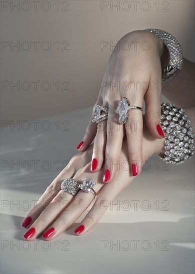 Close up of woman's hands with red nail polish and diamond jewelry.