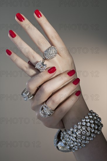 Close up of woman's hands with red nail polish and diamond jewelry.