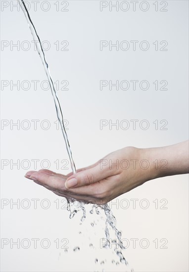 Close up of woman's hands under splashing water.