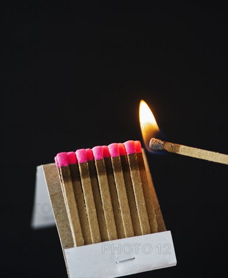Close up of matches with one burning.
