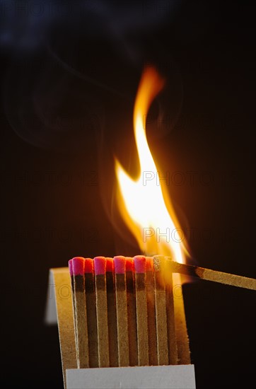 Close up of matches with one burning.