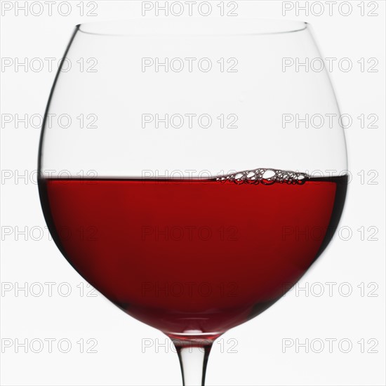 Close up of glass of red wine on white background.
