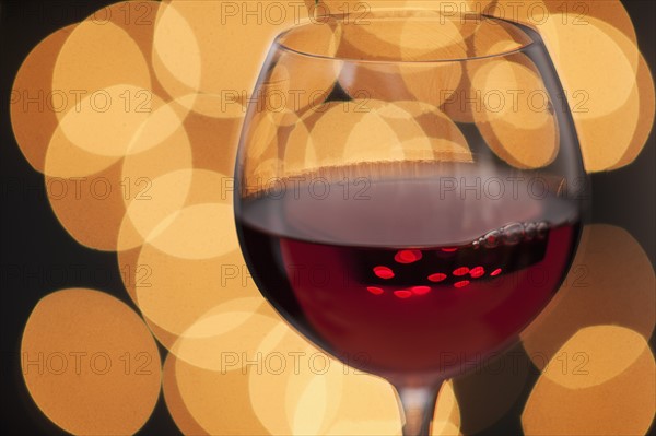 Close up of glass of red wine with defocused lights in background.