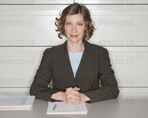 Portrait of woman in office sitting at desk.