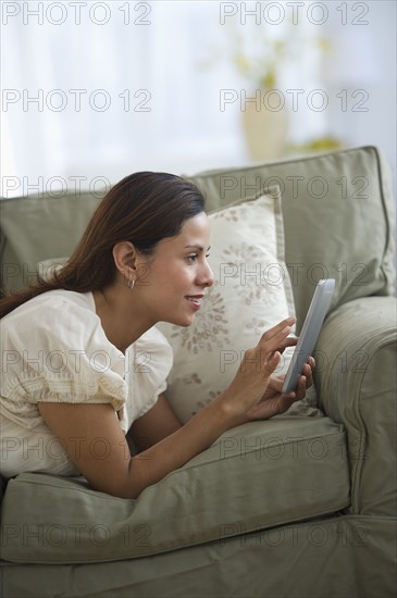 Woman lying on sofa and using digital tablet.