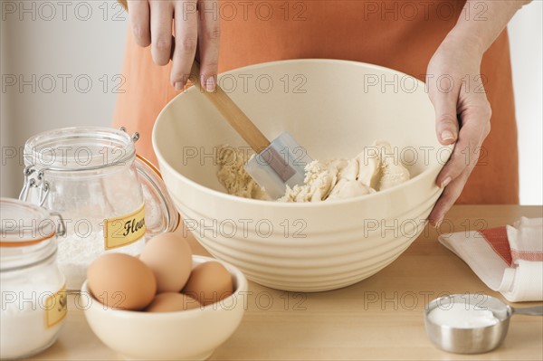 Woman preparing dough in bowl.