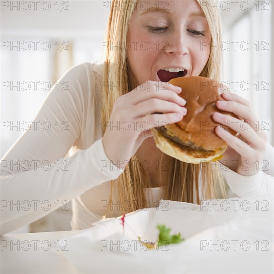 Woman eating hamburger. Photo : Jamie Grill Photography