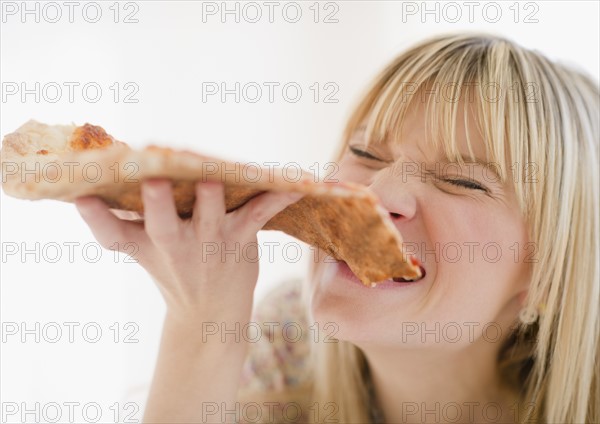 Young woman eating pizza. Photo: Jamie Grill Photography