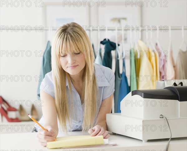 Young businesswoman doing paperwork. Photo : Jamie Grill Photography