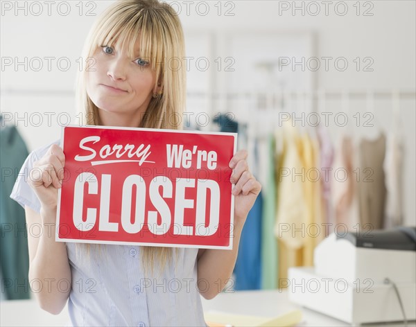 Young woman holding closed sign. Photo : Jamie Grill Photography