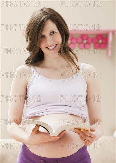 Young pregnant woman holding open book. Photo : Mike Kemp