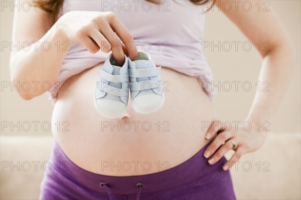 Young pregnant woman holding baby boots. Photo : Mike Kemp