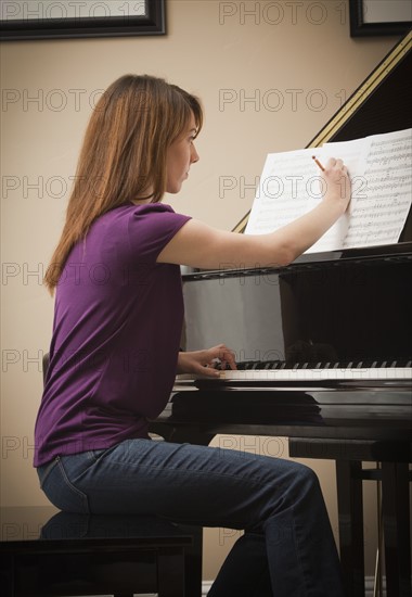 Young woman marking score before setting to play grand piano. Photo : Mike Kemp