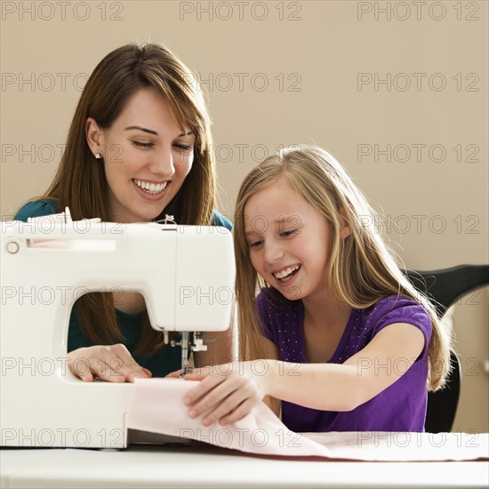 Girl (8-9) and young woman using sewing machine. Photo : Mike Kemp