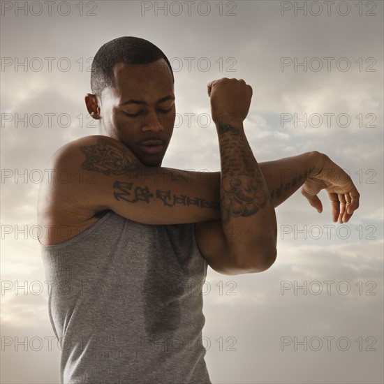 Young man exercising, cloudy sky in background. Photo : Mike Kemp